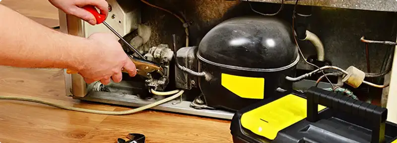 Refrigerator repair technician fixing the compressor and wiring in Towson, MD
