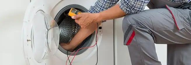 Dryer repair technician inspecting and repairing a clothes dryer in Baltimore, MD