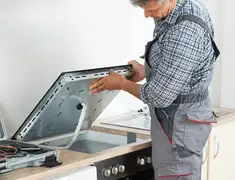 Appliance repair technician installing a built-in cooktop in Baltimore, MD