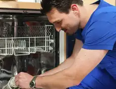 Dishwasher repair technician inspecting and servicing an open dishwasher in Baltimore, MD