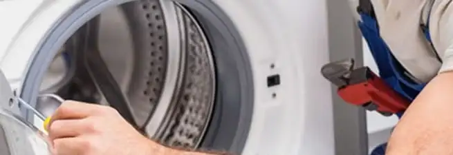 Appliance technician repairing a clothes dryer drum and internal parts in Baltimore, MD
