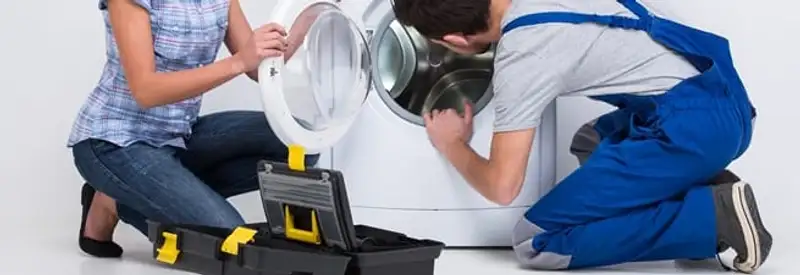 Washer repair technician inspecting a front-load washing machine with tools in Baltimore, MD