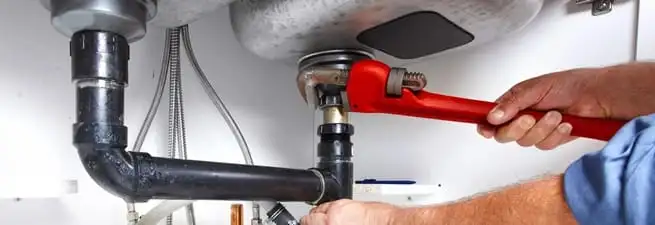 Garbage disposal repair technician tightening the sink drain and disposal connection in Baltimore, MD