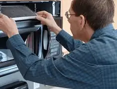 Appliance repair technician replacing a microwave vent filter in Baltimore, MD