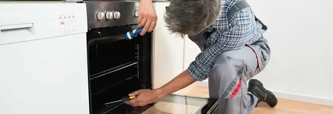 Oven repair technician inspecting and servicing an electric oven in Baltimore, MD