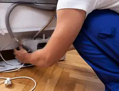 Appliance repair technician fixing refrigerator water line and connections in Baltimore, MD