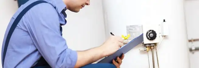 Water heater repair technician inspecting the unit and recording service notes in Baltimore, MD