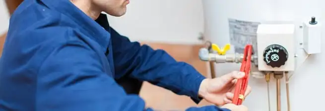 Water heater repair technician adjusting the temperature control and gas valve in Baltimore, MD